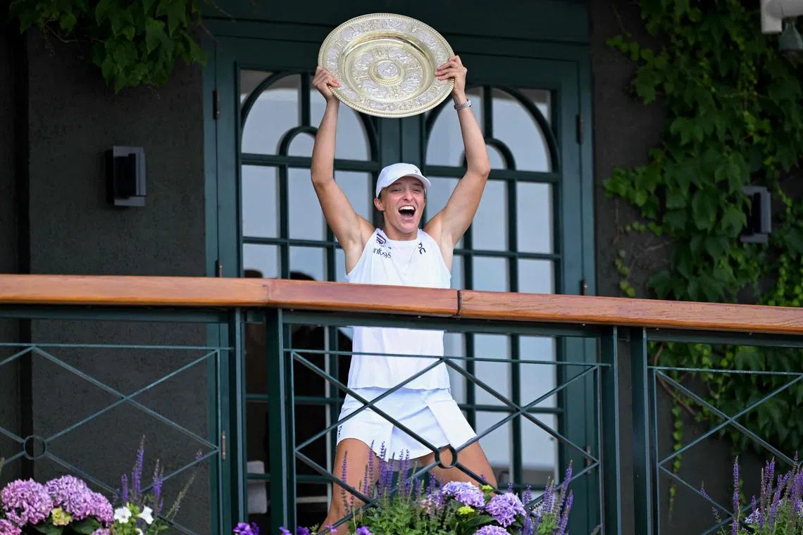 Poland's Iga Swiatek celebrating with the winner's trophy, the Venus Rosewater Dish, as she shows it to the crowd from the Centre Court balcony after winning her Wimbledon women's singles final tennis match against US player Amanda Anisimova 6-0, 6-0 on July 12 at The All England Lawn Tennis and Croquet Club in London.