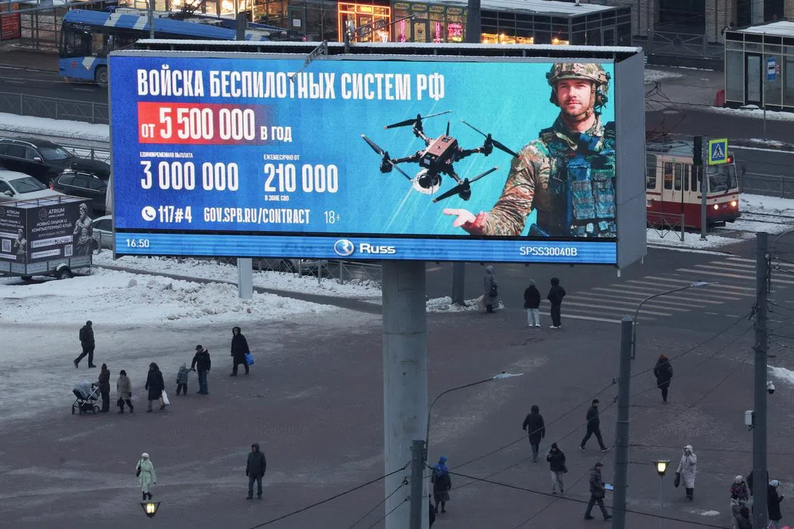 FILE PHOTO: People walk under a digital screen displaying an ad promoting contract military service in the Russian army’s unmanned systems forces, with payment details and contact information, in Saint Petersburg, Russia, January 26, 2026. REUTERS/Anton Vaganov/File Photo