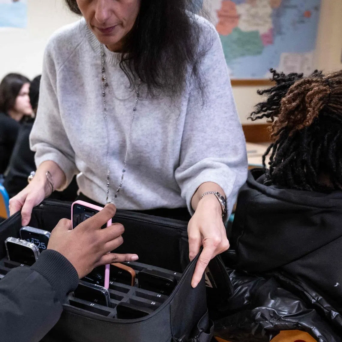 A teacher collects a student's mobile phone at the Jean Mermoz vocational high school in Montsoult, Paris, on Jan 14.