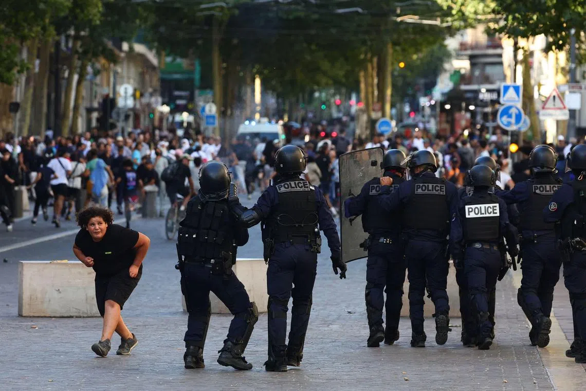 A girl ducks down as she walks past police officers preparing to disperse protesters with tear gas, in Marseille, southern France.
