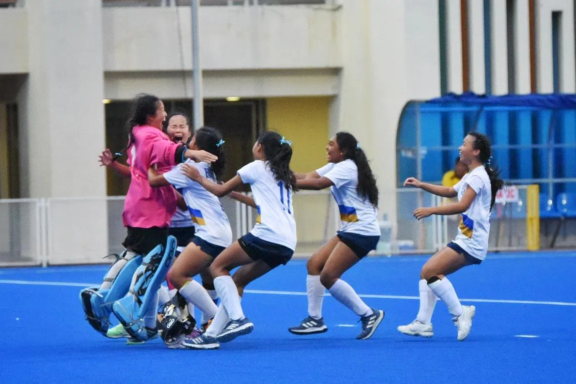 Eunoia Junior College players rush to embrace goalkeeper Rainelle Goh (pink) whose penalty save clinched their third A Division girls' hockey title at Sengkang Hockey Stadium on May 13.