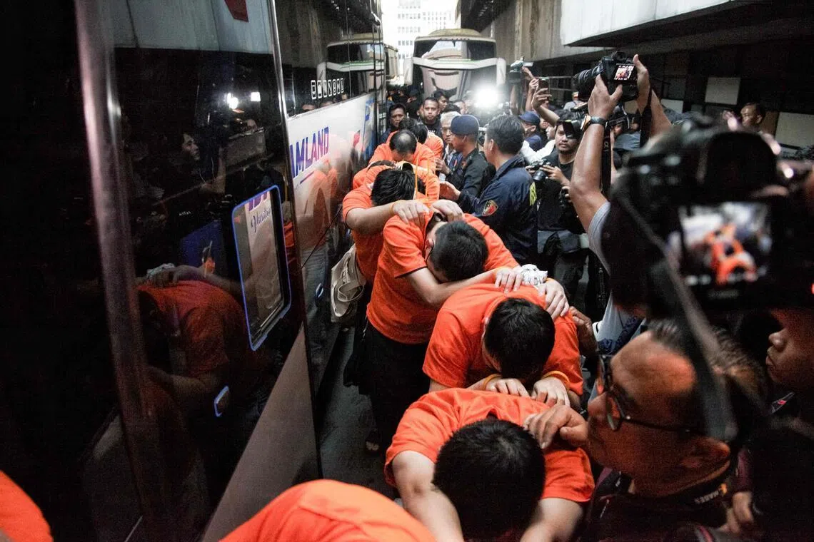 Suspected online gambling operators (in orange) walk towards buses for transfer after a police raid at the Hayam Wuruk Plaza office building in Jakarta on May 10.