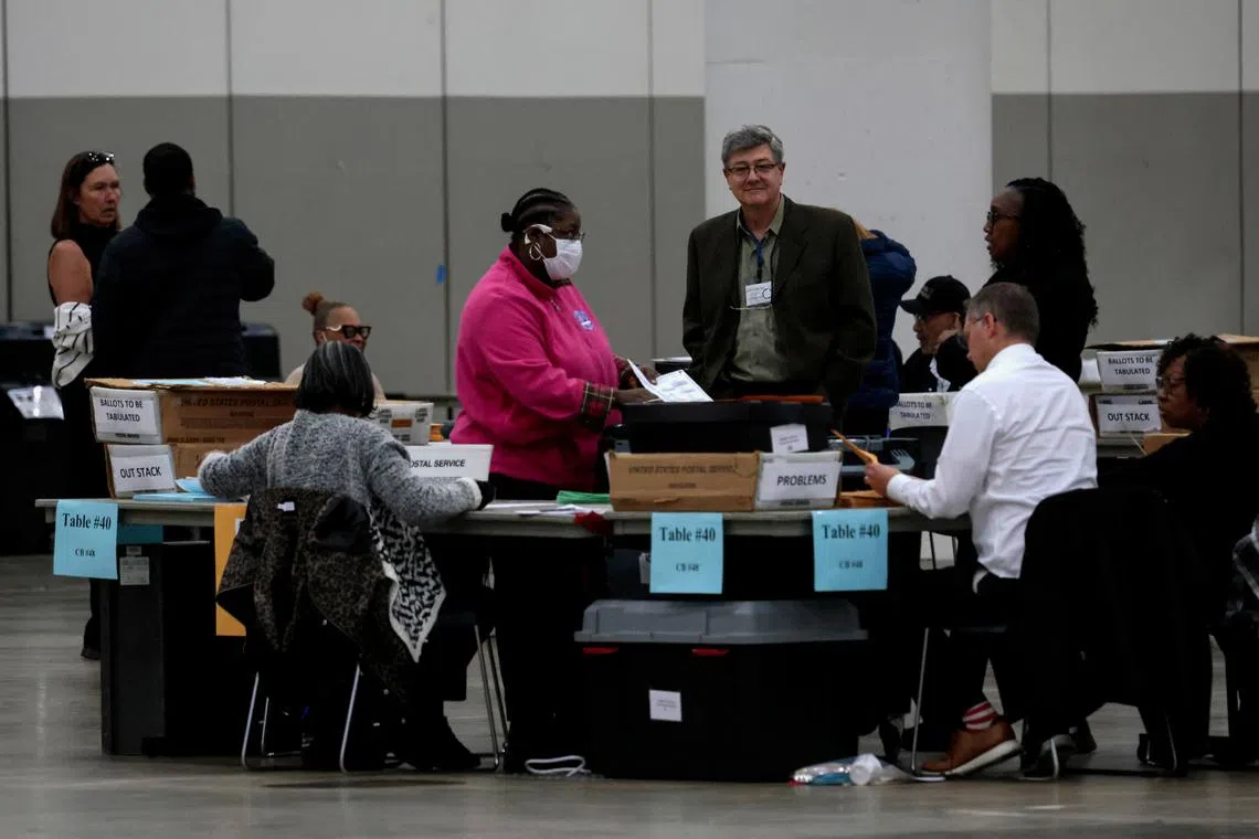 A vote challenger watches as election clerks process absentee ballots for the presidential election and feed them into a tabulator ahead of the polls closing November 5 at the Huntington Place in Detroit, Michigan, U.S. October 28, 2024.  REUTERS/Rebecca Cook