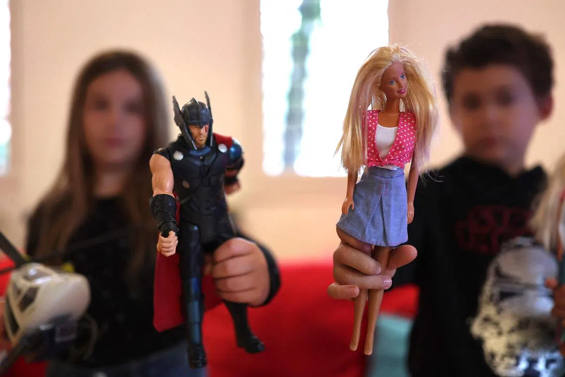 A girl (L) holds an action figure and a boy holds a Barbie doll as they play together in Madrid on December 18, 2022. - Cars for girls, dolls for boys and no more pink and blue: for Spain's left-wing government and the toy industry, it's game over for gender stereotypes when it comes to the country's littlest citizens. (Photo by THOMAS COEX / AFP)