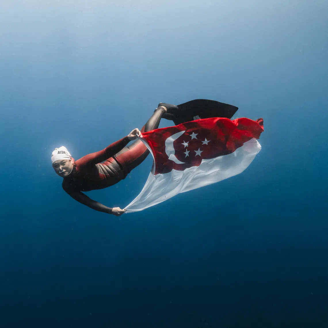 Patricia Ong with a Singapore flag underwater in Manado Bay, Indonesia, after setting a national record on Aug 9.