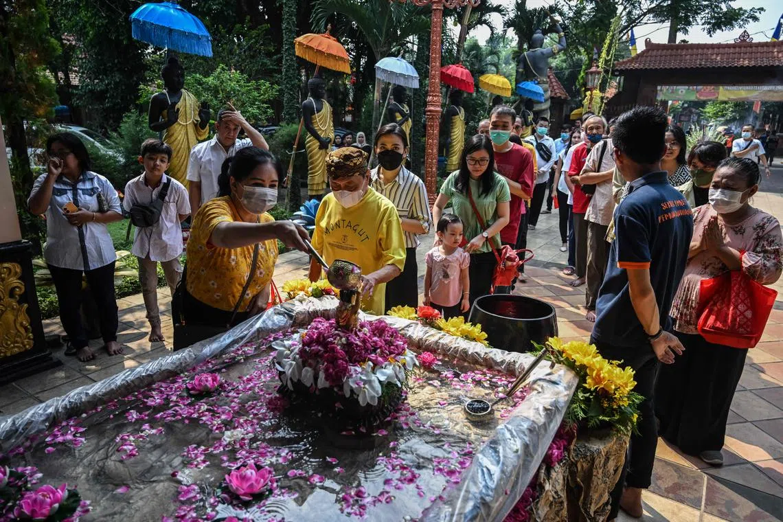 Buddhist devotees pour holy water over a baby Prince Siddhartha Gautama statue at Maha Vihara Mojopahit temple in Mojokerto on June 4, 2023, as Buddha devotees celebrate Vesak day. 