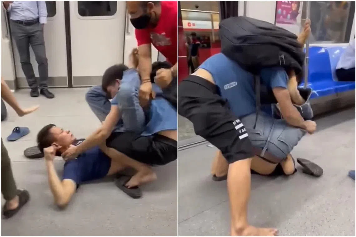 A man clad in a dark blue shirt sprawled on the train floor, punching and kicking the other man, who was wearing a light blue shirt.