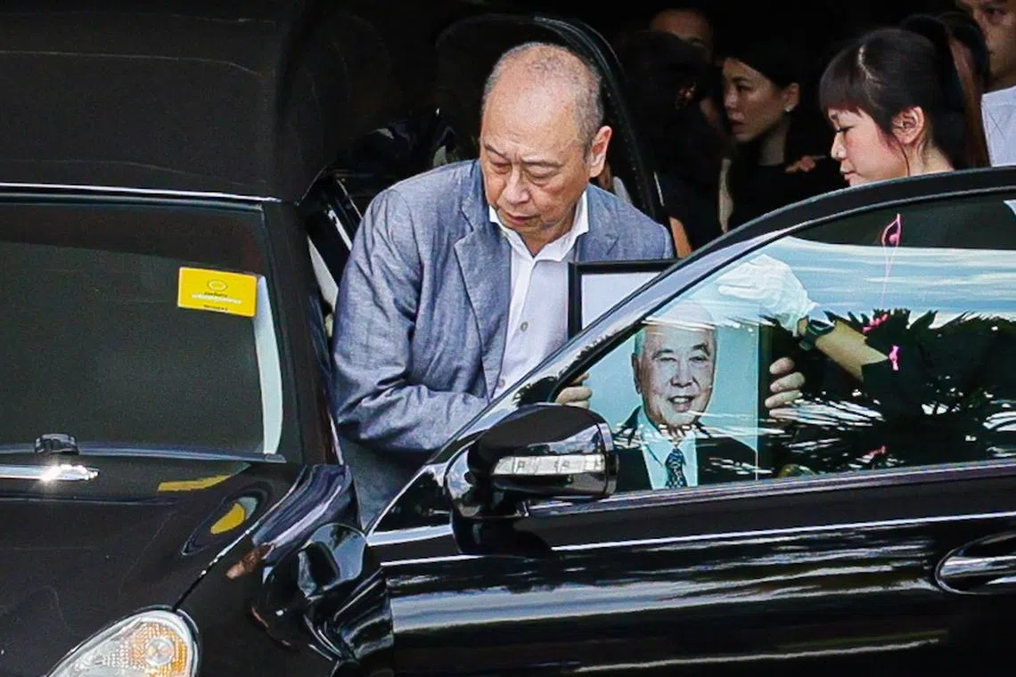 Mr Wee Ee Cheong (in blue jacket) carrying his father's portrait as he boards the hearse carrying Dr Wee Cho Yaw’s body before departing the Woodlands Memorial on Feb 7, 2024.