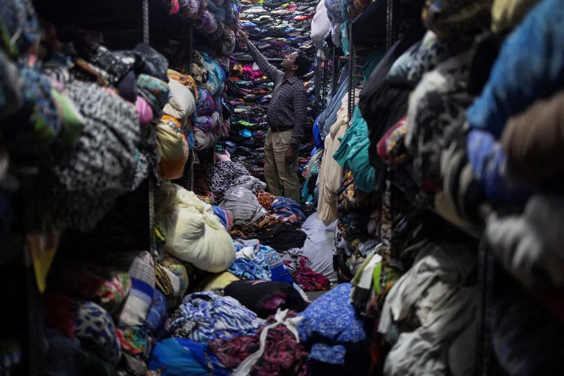 A worker looks for a fabric for dresses inside a store at a garment manufacturing unit in Noida, India, on Aug 7.