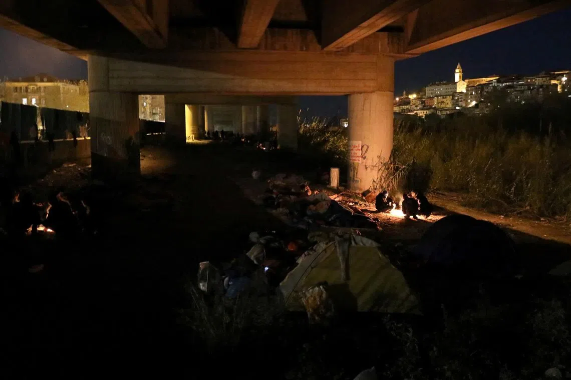 FILE PHOTO: Migrants mostly from the Darfur region of western Sudan warm up by a fire under a highway bypass where they have been sheltering from the weather as they prepare to attempt to cross the Italian border into France, in the Mediterranean coastal town of Ventimiglia, northern Italy, December 3, 2017. REUTERS/Siegfried Modola  SEARCH \"MODOLA ALPS\"/File Photo