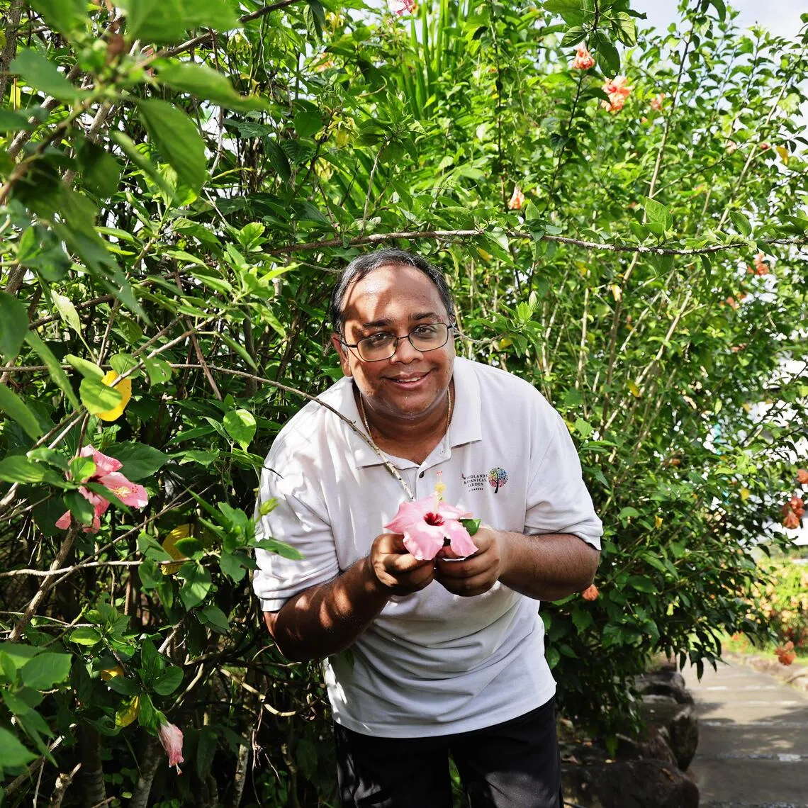 Mr Ganesh Kumar, founder of Woodlands Botanical Garden, with a pink hibiscus – the first plant he planted at the garden