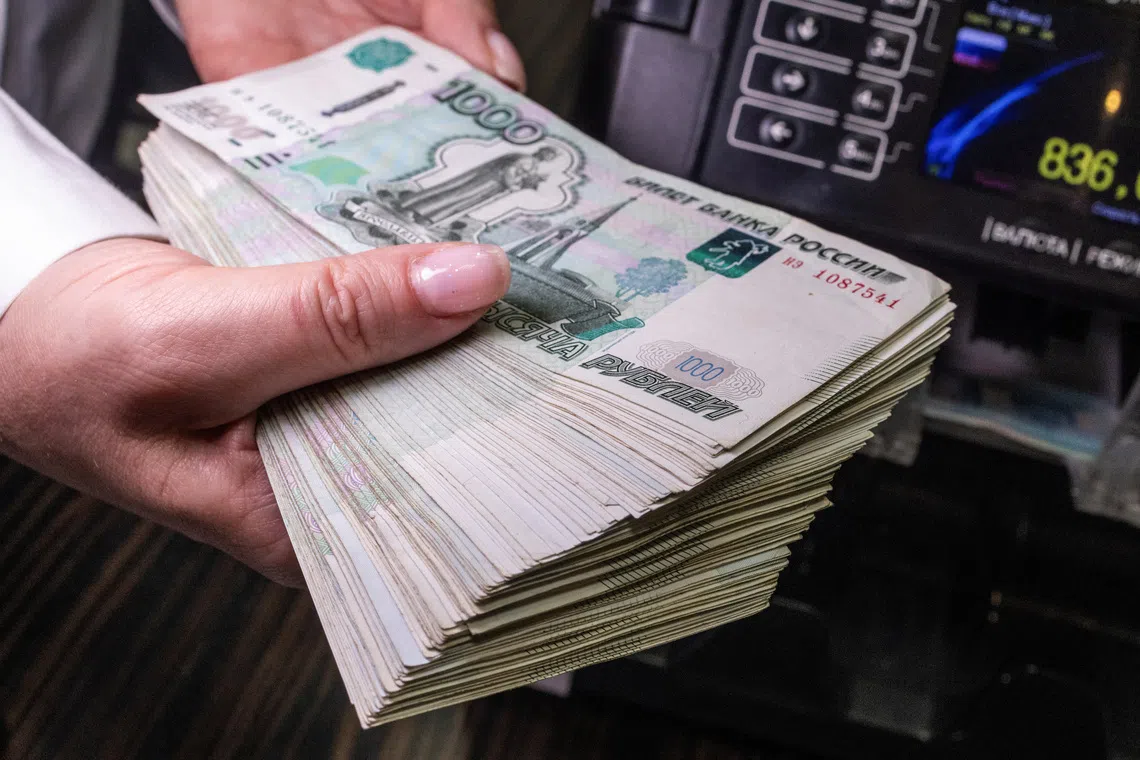 An employee holds Russian 1000-rouble banknotes next to a currency counting machine in a bank office in Moscow, Russia, in this illustration picture taken October 9, 2023. REUTERS/Maxim Shemetov