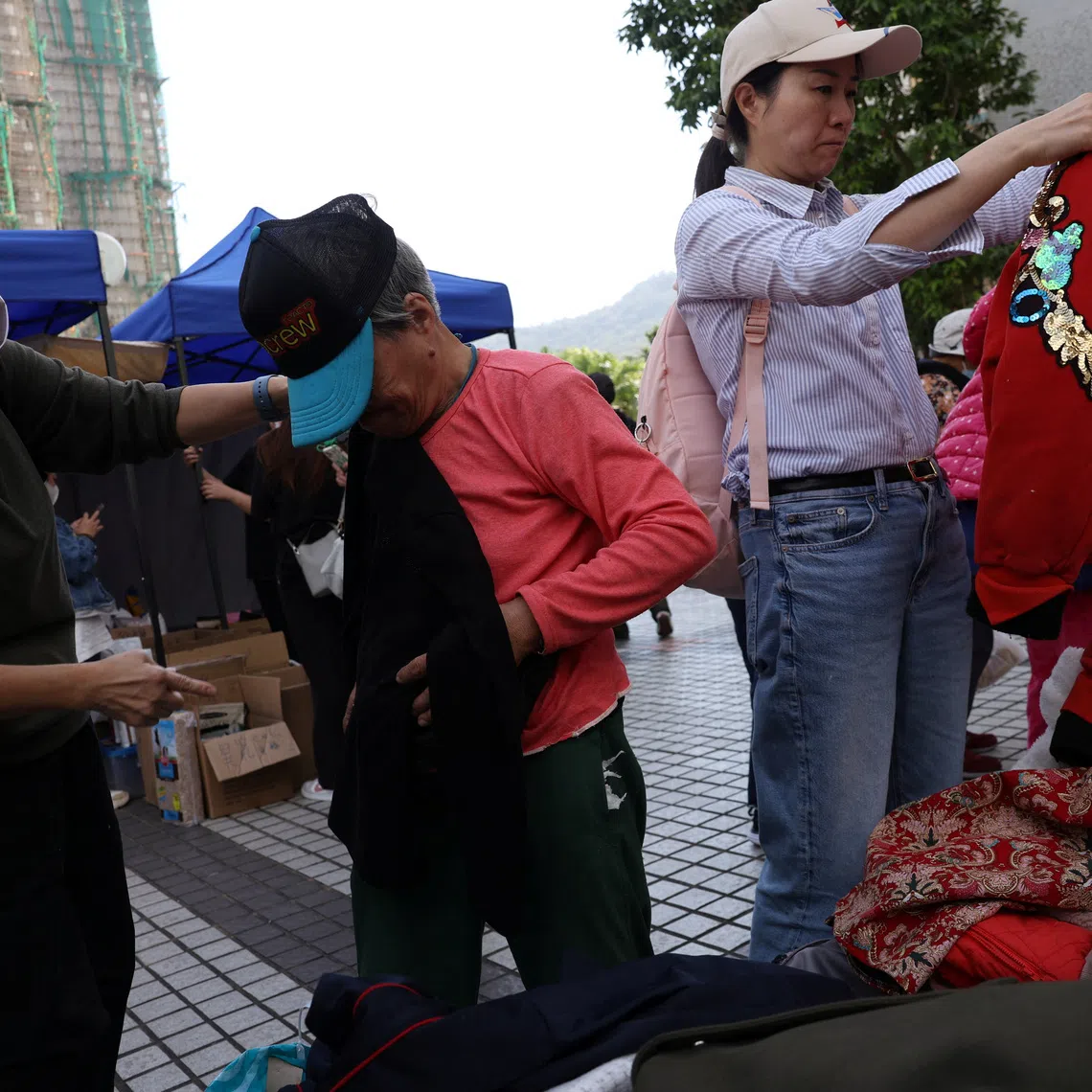 A volunteer helps an elderly resident affected by the deadly fire at the Wang Fuk Court housing complex, at a support station nearby in Hong Kong, China November 28, 2025. REUTERS/Amr Alfiky