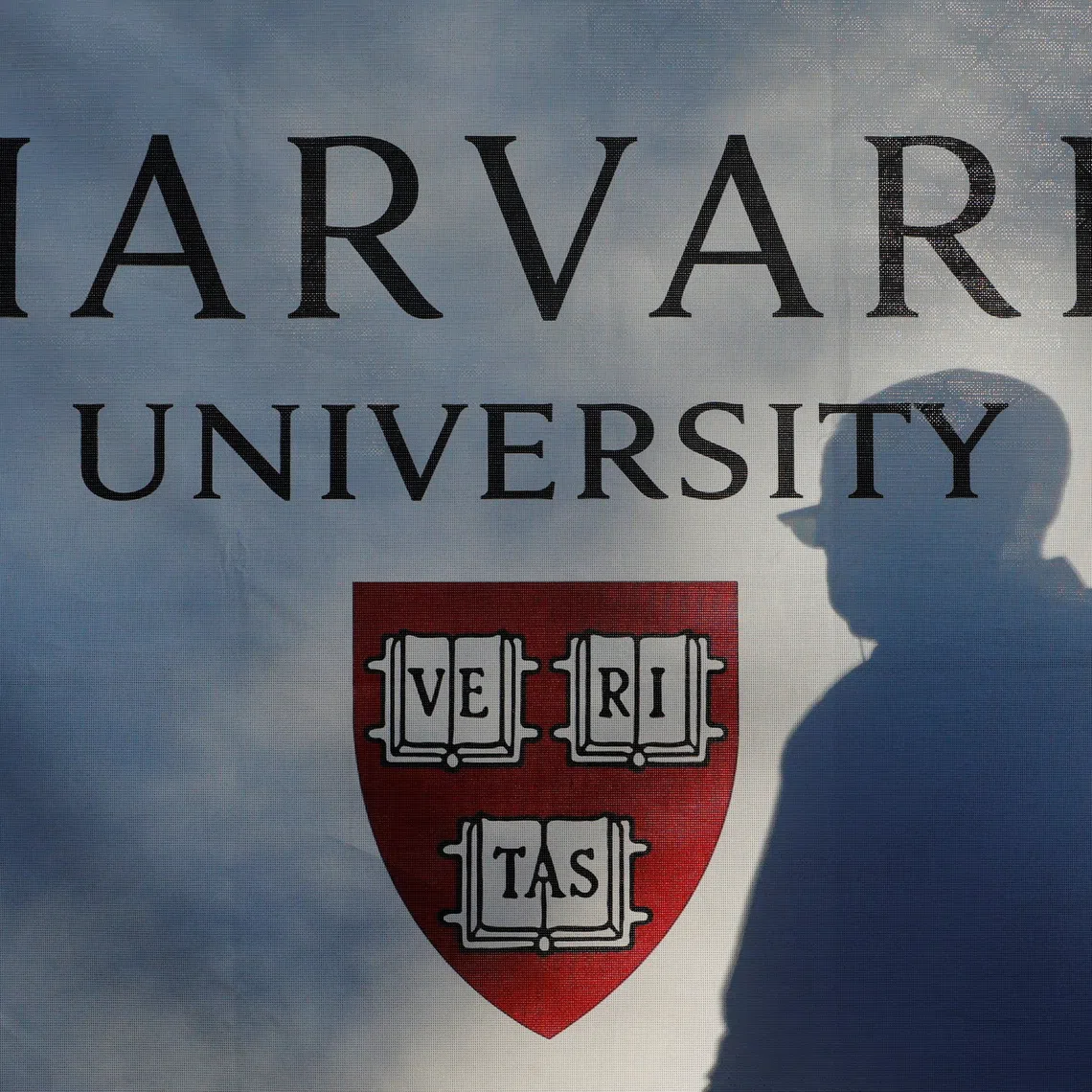 A pedestrian casts a shadow on a Harvard University sign after U.S. President Donald Trump said that his administration was close to a deal with Harvard University, in Cambridge, Massachusetts, U.S., September 30, 2025.   REUTERS/Brian Snyder