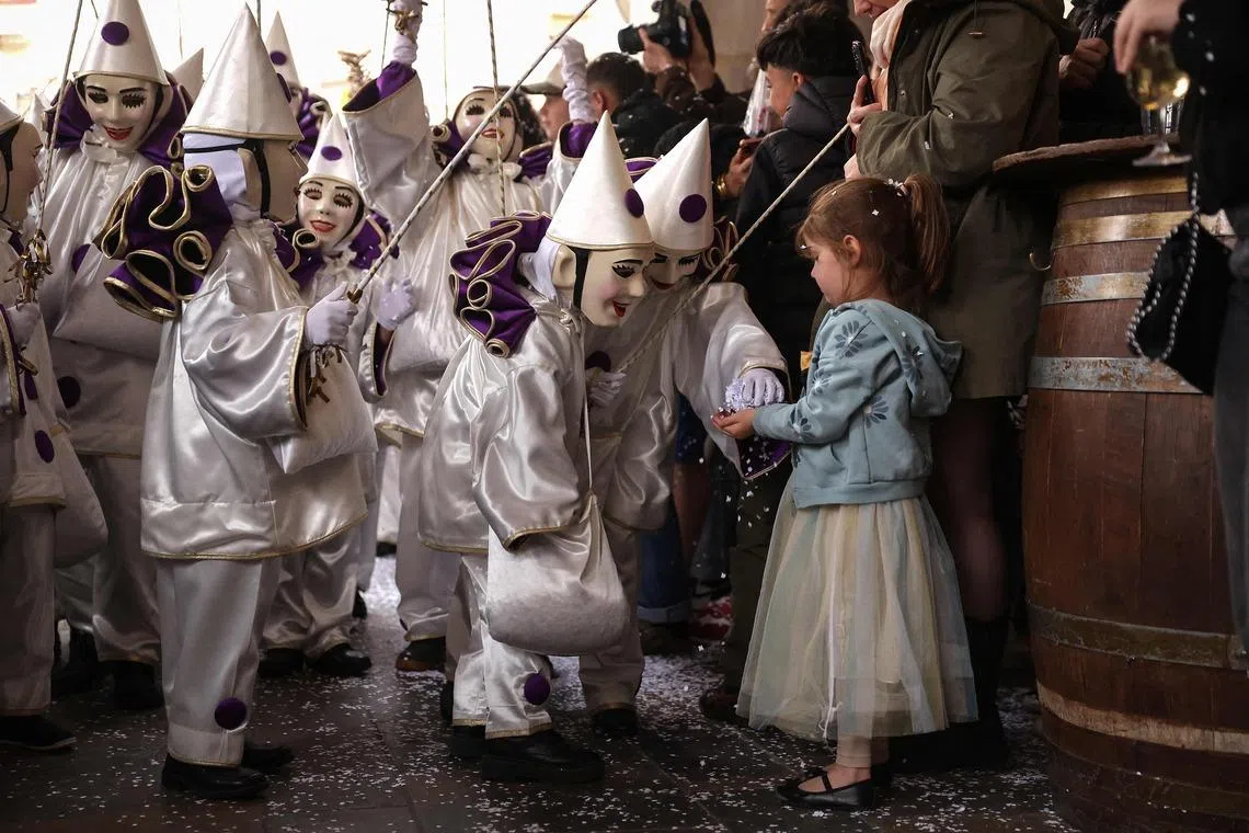 Masked performers offering confetti to a girl during the last day of the city's carnival in the historical centre of Limoux, southern France, on March 22.