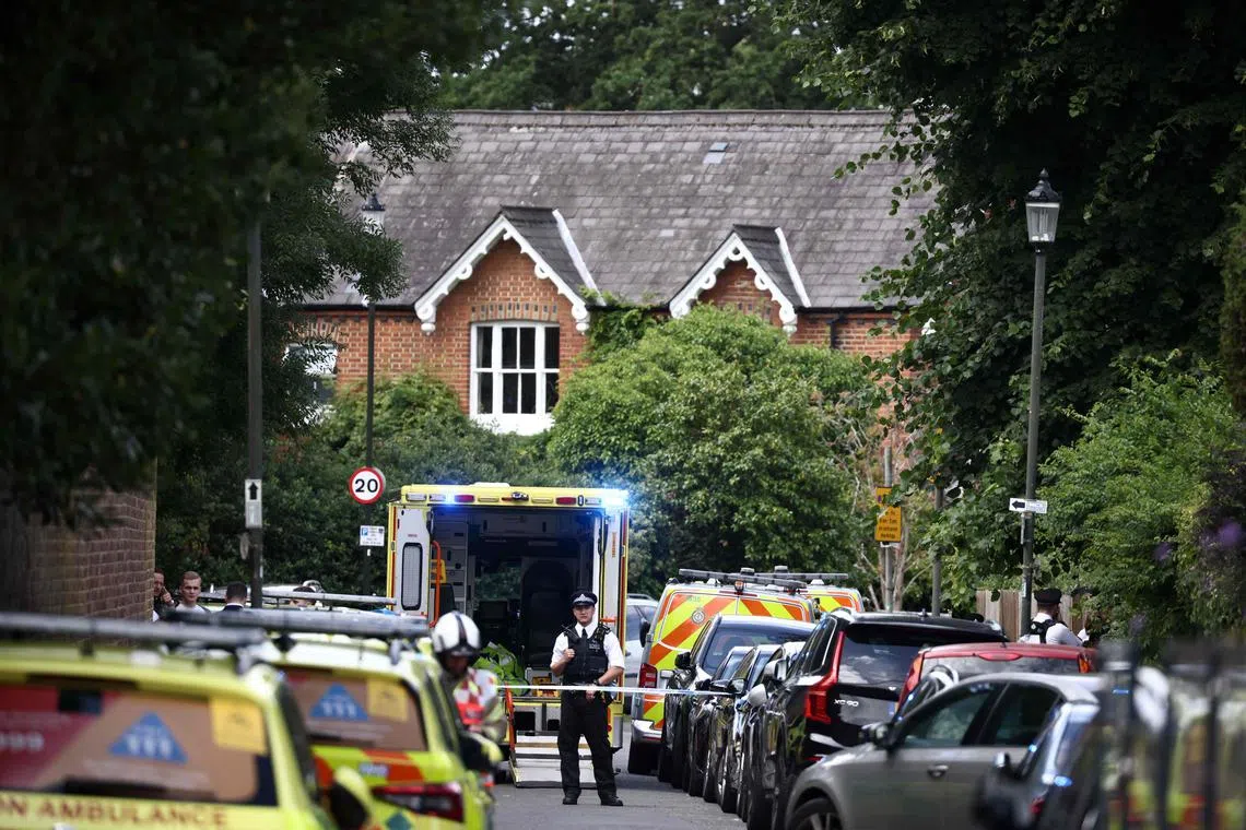 A police officer stands next to an ambulance behind a cordon following a car collision at the private Study Prep girls' school in Wimbledon.