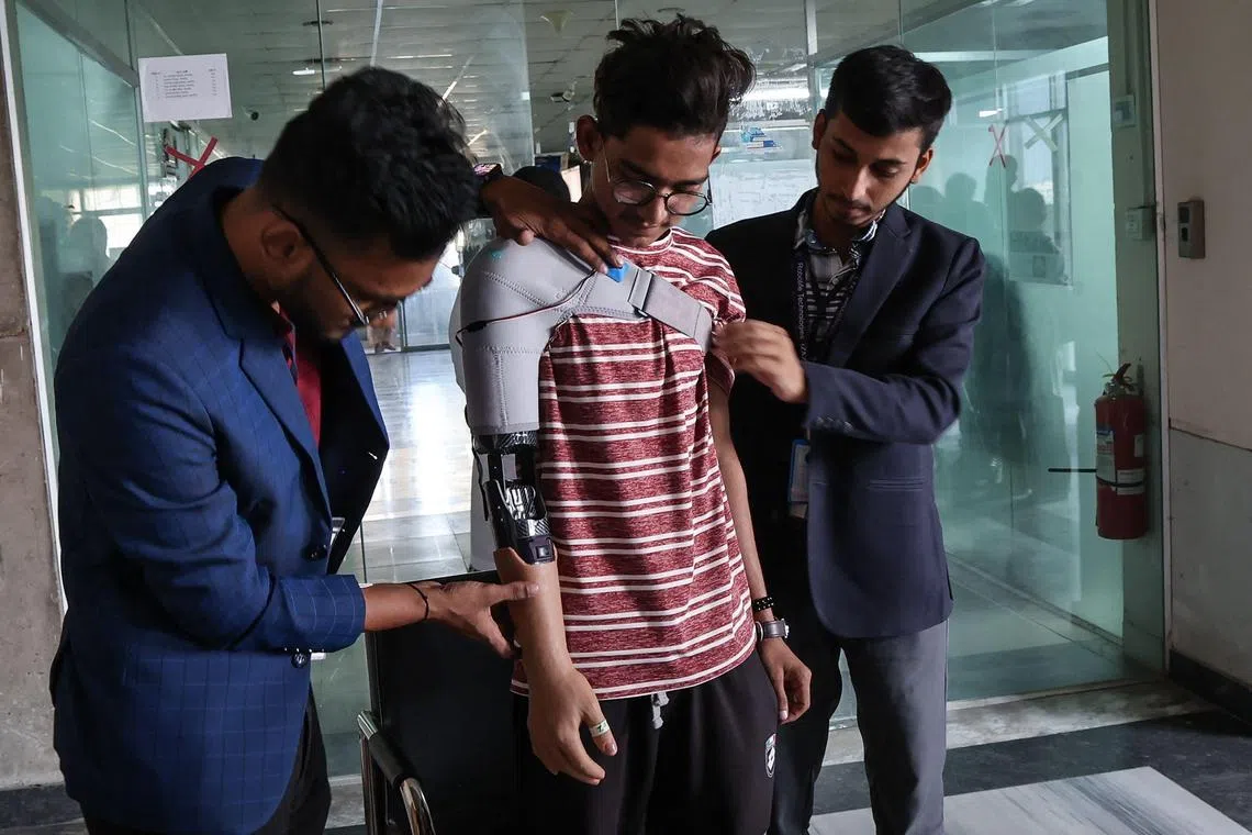 TOPSHOT - A protester who lost his arm in July's students' revolution tries out a prosthetic arm manufactured by Robolife Technologies in Dhaka on November 21, 2024. Squeezing rubber-covered prosthetic hands, Bangladesh students wounded during the deadly revolution to topple autocratic leader Sheikh Hasina test out robotic arms to replace their lost limbs. (Photo by Abdul Goni / AFP)