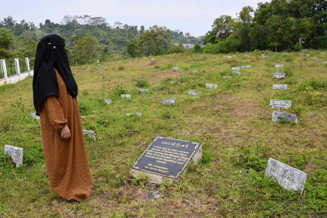 In this photo taken on September 8, 2026, Sophia Aminolla stands amongst the graves of victims of the Marawi siege, on the outkirts of Marawi, Lanao del sur province on the southern island of Mindanao. Sophia Aminolla, a nurse and mother of two, does not know if her missing younger brother Amerel is among those lying beneath the numbered graves.From May to October of 2017, Islamic State-linked gunmen and the Philippine military fought brutal house-to-house battles that turned Marawi's 400-hectare business district into a ghost town. (Photo by Ted ALJIBE / AFP) / To go with AFP story Philippines-vote-unrest-missing, FOCUS by Cecil MORELLA, Chad WILLIAMS