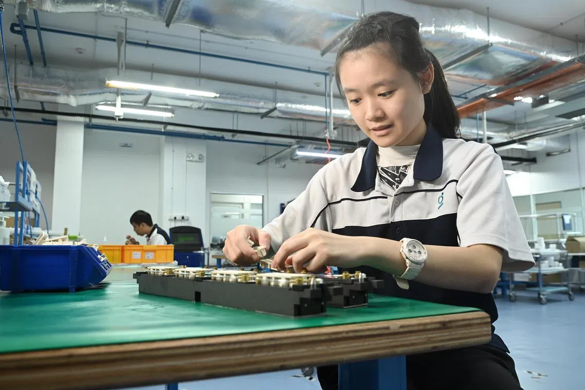 Profile photo taken on 28 April  2023 of Ms You Kai Xuan, 22 . 
Kai Xuan is working on a mechanical assembly . She is the assembly technician with autism at Grand Venture Technology. Kai Xuan, 22, graduated from ITE College East in 2021 with a Nitec in Infocomm Technology. Trampolene helped refer Kai Xuan to an inclusive employer, Grand Venture Technology, by presenting video evidence of her work ability. Grand Venture Technology agreed to begin with a work trial that included close job support from Trampolene’s team. Trampolene provided training and guidance to Kai Xuan’s supervisor and colleagues to facilitate effective communication and to help her remain focused in the event of any distractions. As a result, Kai Xuan has successfully completed her probationary period and is gainfully employed for more than 9 months.