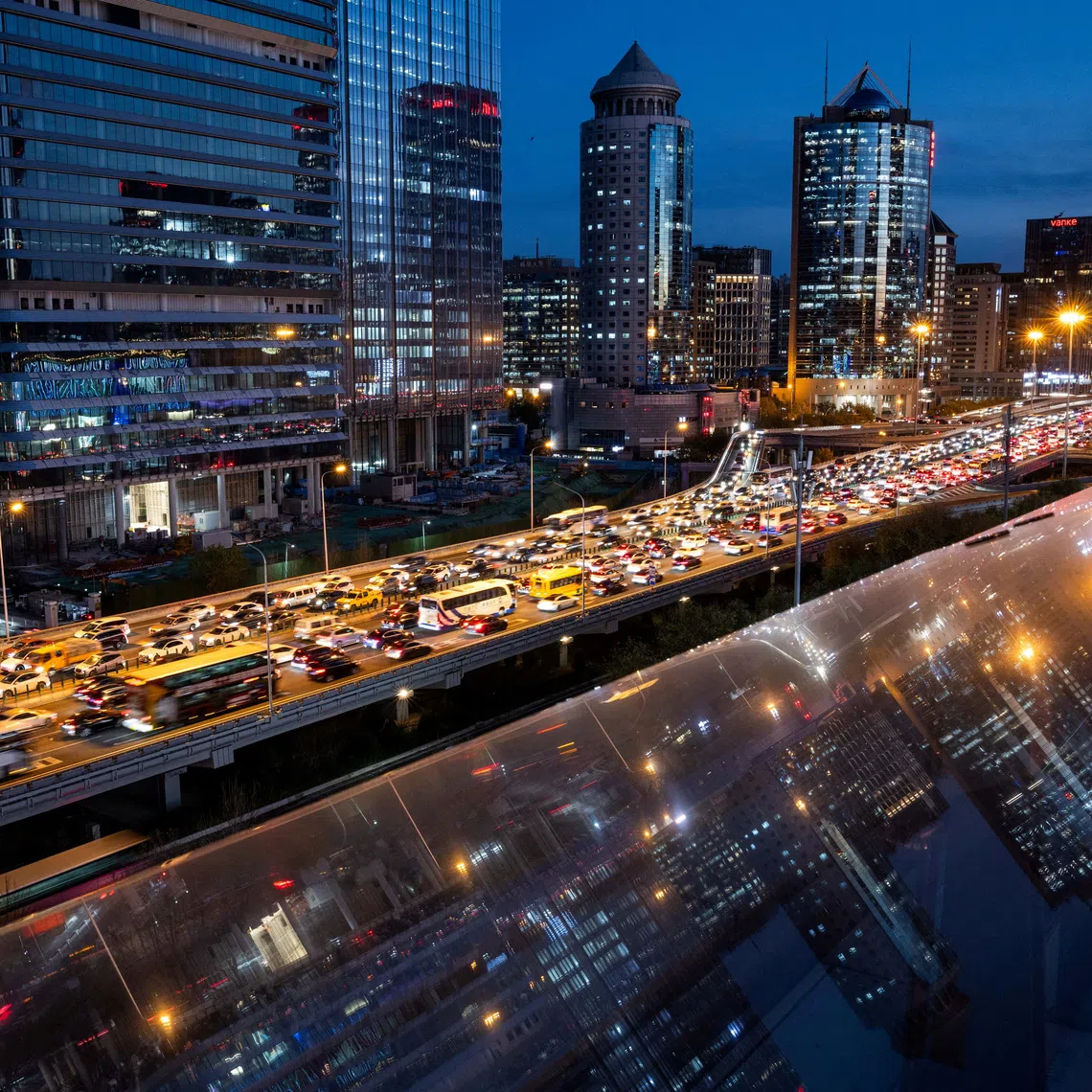 Cars are stuck in traffic on an elevated highway as buildings are reflected on a glass surface in Beijing's central business district (CBD), China, November 12, 2025. REUTERS/Maxim Shemetov