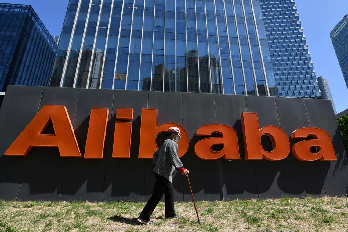 (FILES) A woman walks past an Alibaba sign outside the company's office in Beijing on April 13, 2021. Chinese e-commerce giant Alibaba reported a 29 percent fall in quarterly profit on August 15, 2024, as it battles sluggish consumption during an economic slowdown. (Photo by GREG BAKER / AFP)