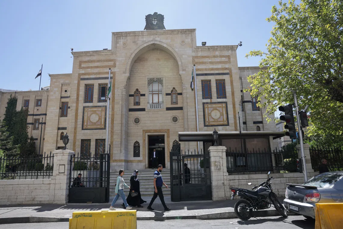 A group of civilians walk past the main gate of the Syrian parliament building, in Damascus, Syria September 3, 2025. REUTERS/Khalil Ashawi