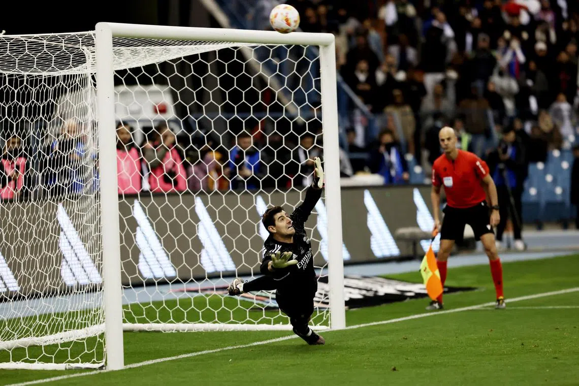 Real Madrid's Thibaut Courtois dives as Valencia's Eray Comert shoots over during the penalty shoot-out.