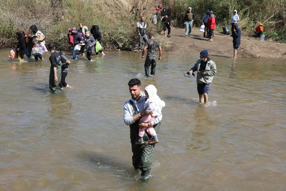 FILE PHOTO: Alawite Syrians, who fled the violence in western Syria, walk in Nahr El Kabir River, after the reported mass killings of Alawite minority members, in Akkar, Lebanon March 11, 2025. REUTERS/Mohamed Azakir/File Photo