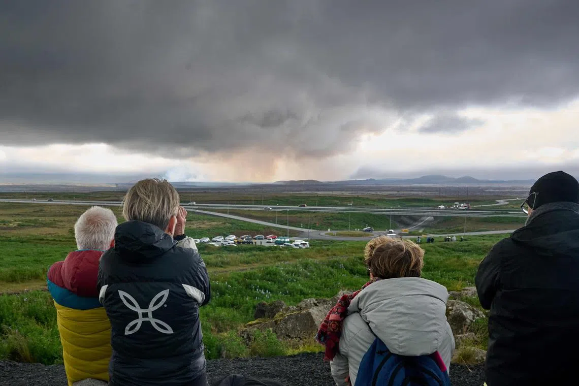 Tourists watching smoke and lava emanating from a volcano on Iceland's Reykjanes peninsula on July 16.