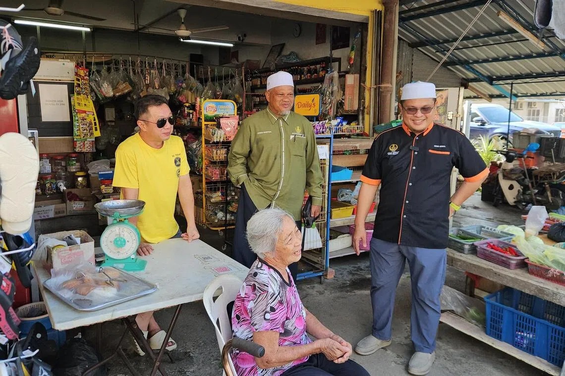 Northern Perak PAS assemblyman Akmal Kamarudin (right) and his Mandarin-fluent right-hand man Ahmad Bakhtier Muslim (center, green shirt) deliver aid to a Chinese senior citizen on Aug 22.