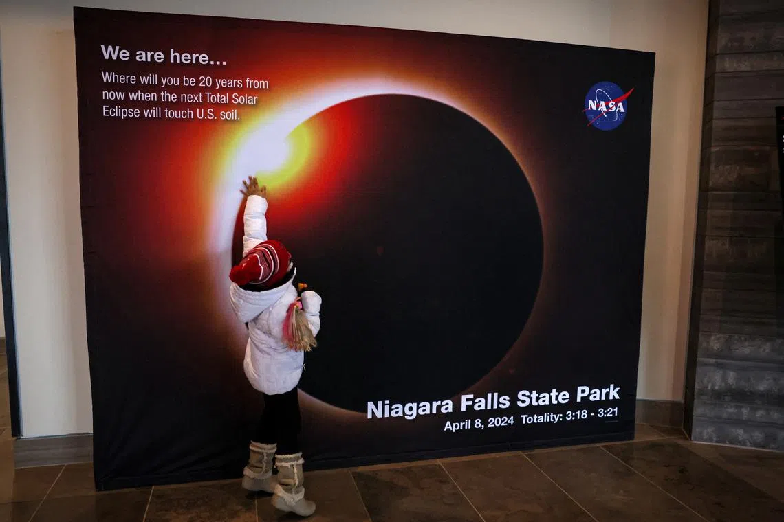 A child touches a NASA countdown display, ahead of the Solar Eclipse that will take place across parts of the United States and Canada on April 8, at Niagara Falls, New York, U.S., April 5, 2024. REUTERS/Brendan McDermid
