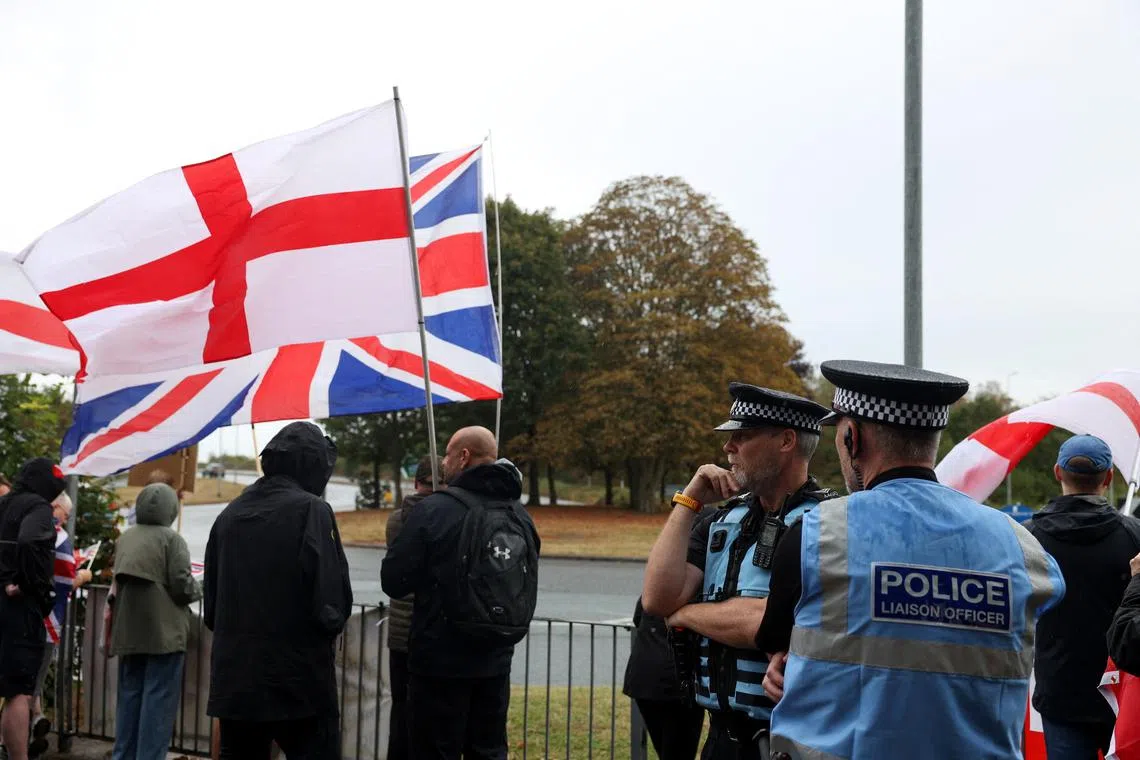 Police officers stand as people gather near the IHG Holiday Inn in Woolston during a protest over asylum seekers being housed in the hotel, in Warrington, Britain, August 30, 2025. REUTERS/Temilade Adelaja