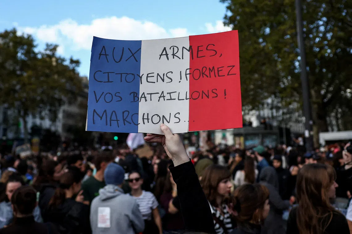 A protester holds a placard in the colours of the French flag reading \"To arms, citizens! Form your battalions! Let's march\", during a demonstration by French high school and university students in Paris as part of a nationwide day of protests and blockades supported by teachers and school parents to demand better school conditions in France, October 8, 2026. REUTERS/Abdul Saboor