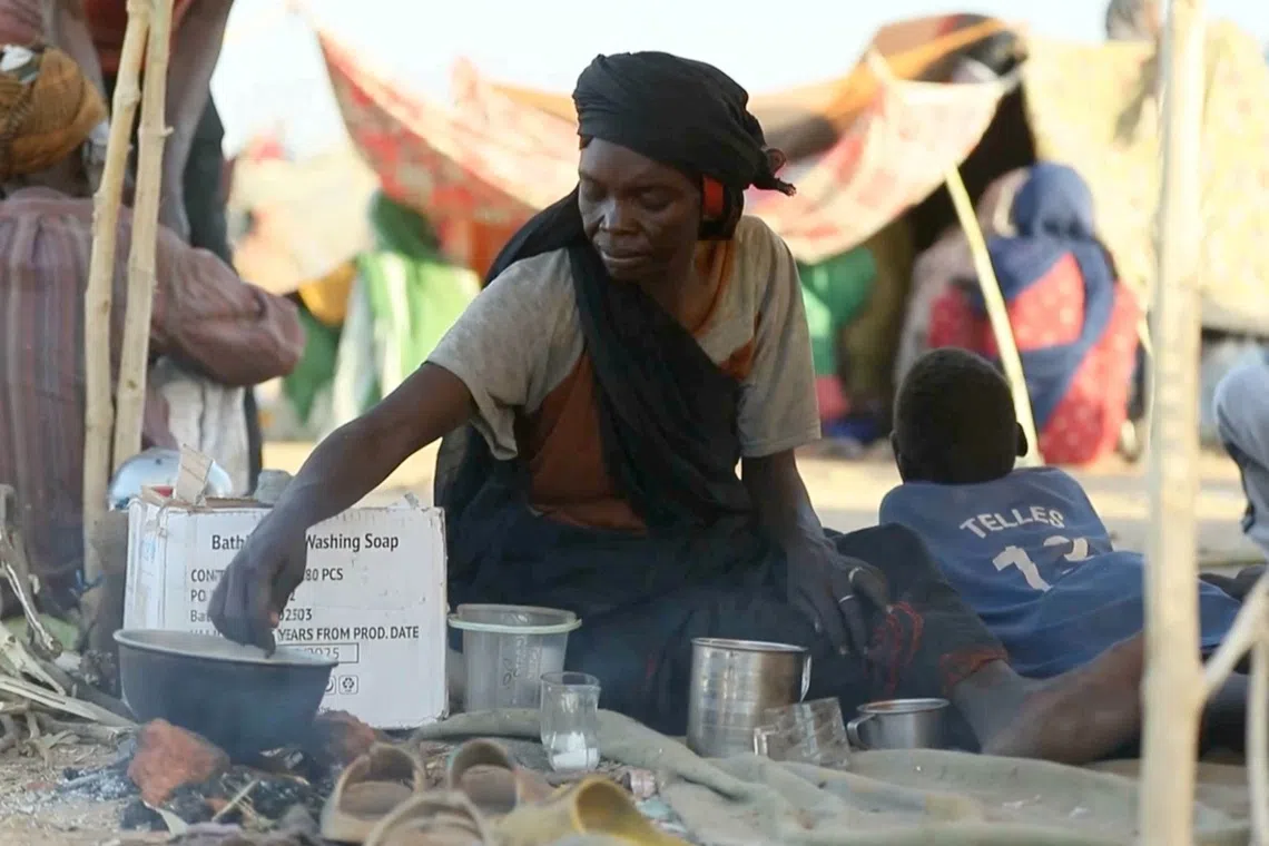 A displaced Sudanese woman makes tea while others gather and sit in makeshift tents after fleeing Al-Fashir city in Darfur, in Tawila, Sudan, October 29, 2025, in this still image taken from a Reuters' video. REUTERS/Mohamed Jamal