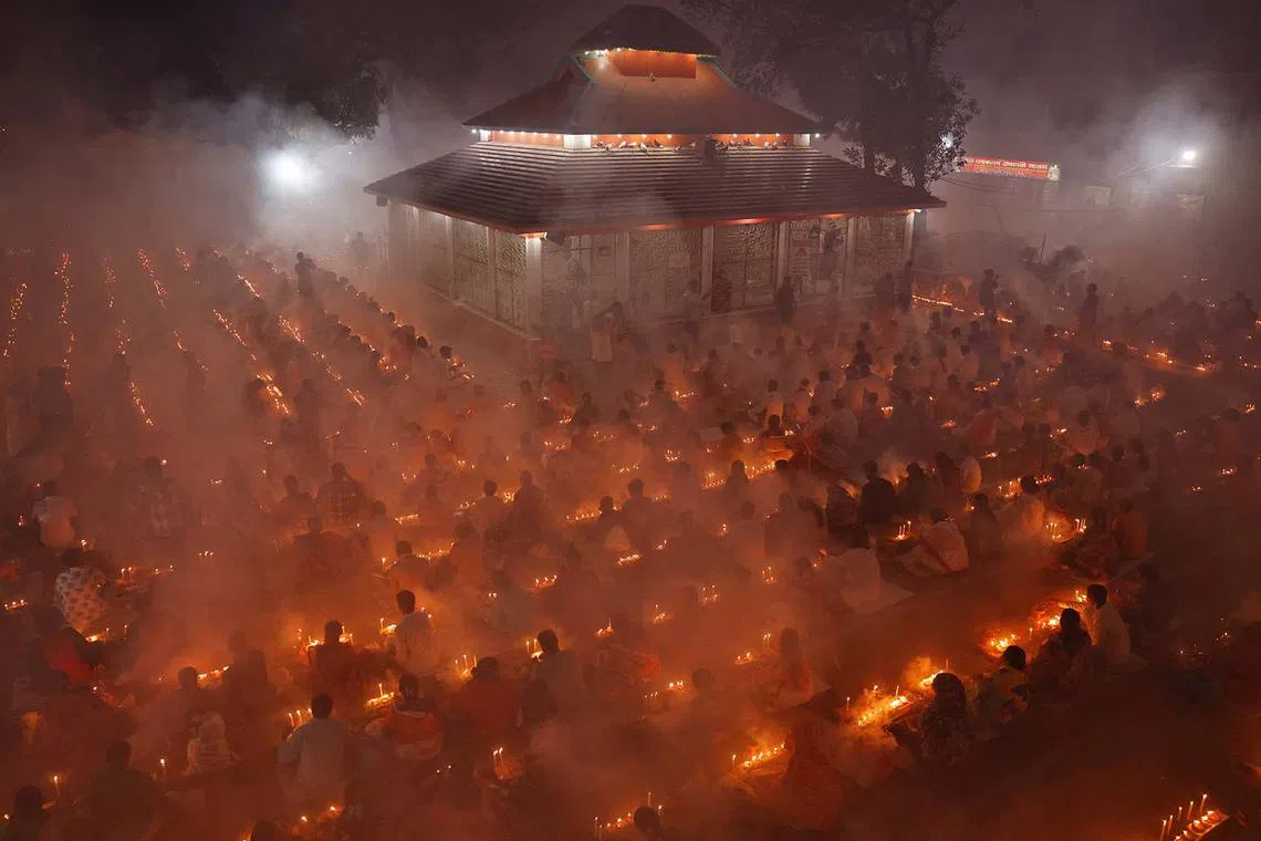 Hindu devotees sitting together in front of oil lamps and praying to Lokenath Brahmachari, a Hindu saint and philosopher, as they observe the Rakher Upobash festival at a temple in Narayanganj, Bangladesh, Nov 5, 2024. 