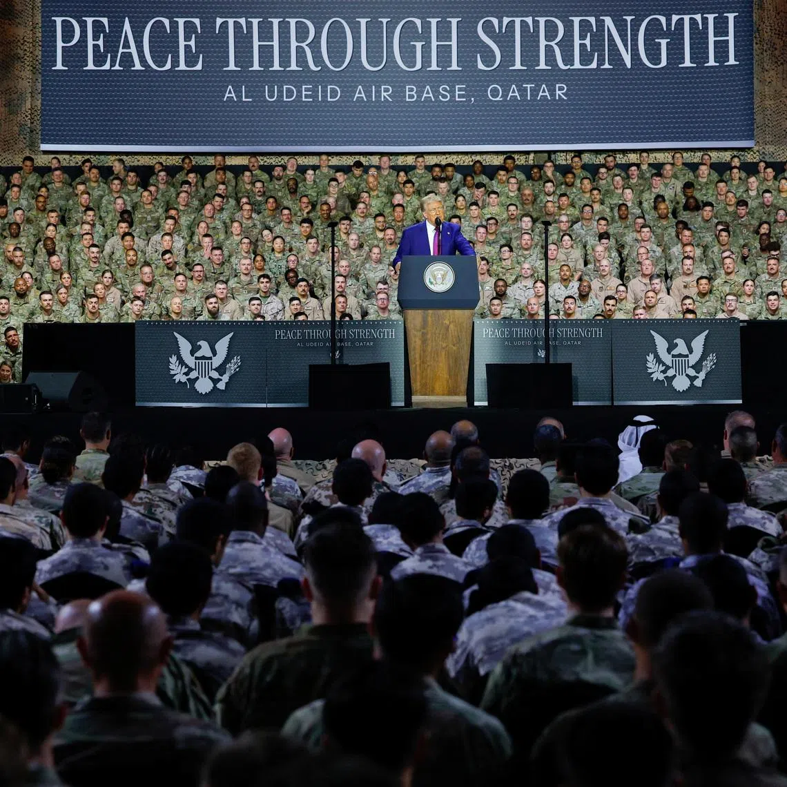 U.S. President Donald Trump delivers remarks to U.S. troops, in front of a banner reading, \"Peace Through Strength\", during a visit to Al Udeid Air Base in Doha, Qatar, May 15, 2025. REUTERS/Brian Snyder