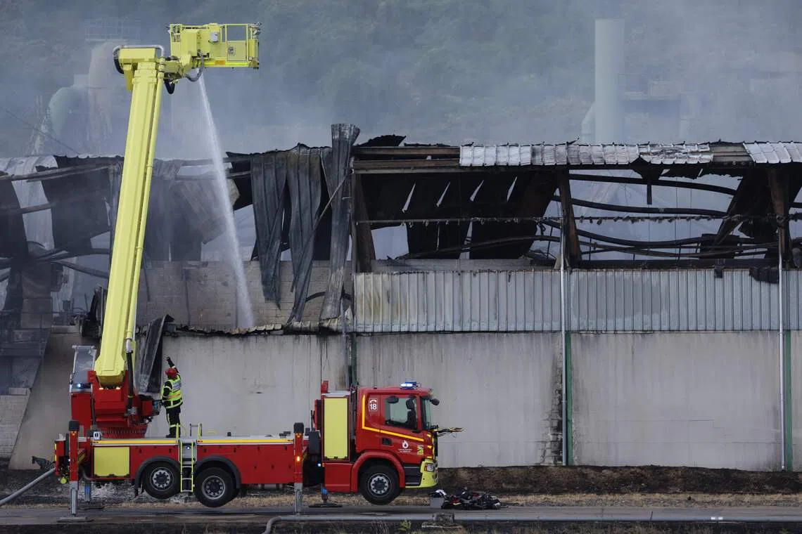 A French firefighter sprays water with a truck at an industrial warehouse in the north-eastern French village of Gandrange on Aug 2. The fire spewed foul smoke that gave residents headaches.