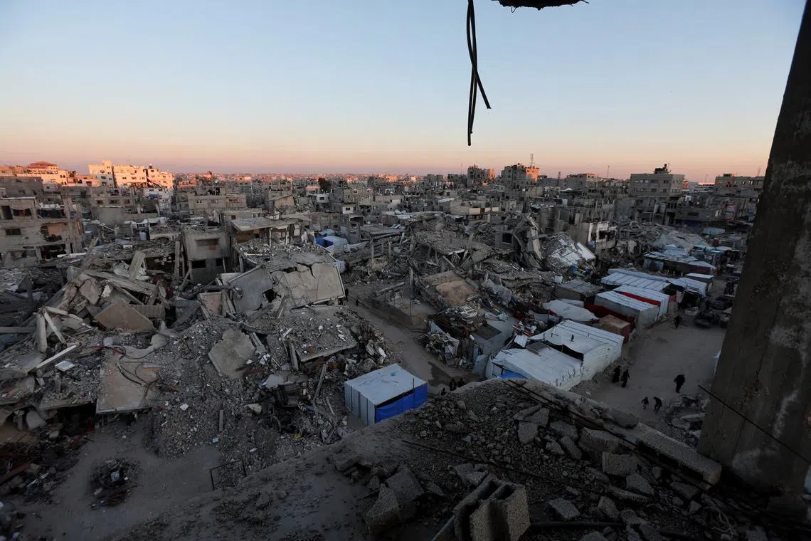 Palestinians walk near the rubble of buildings, amid a ceasefire between Israel and Hamas, in Khan Younis, in the southern Gaza Strip, February 27, 2025. REUTERS/Ramadan Abed