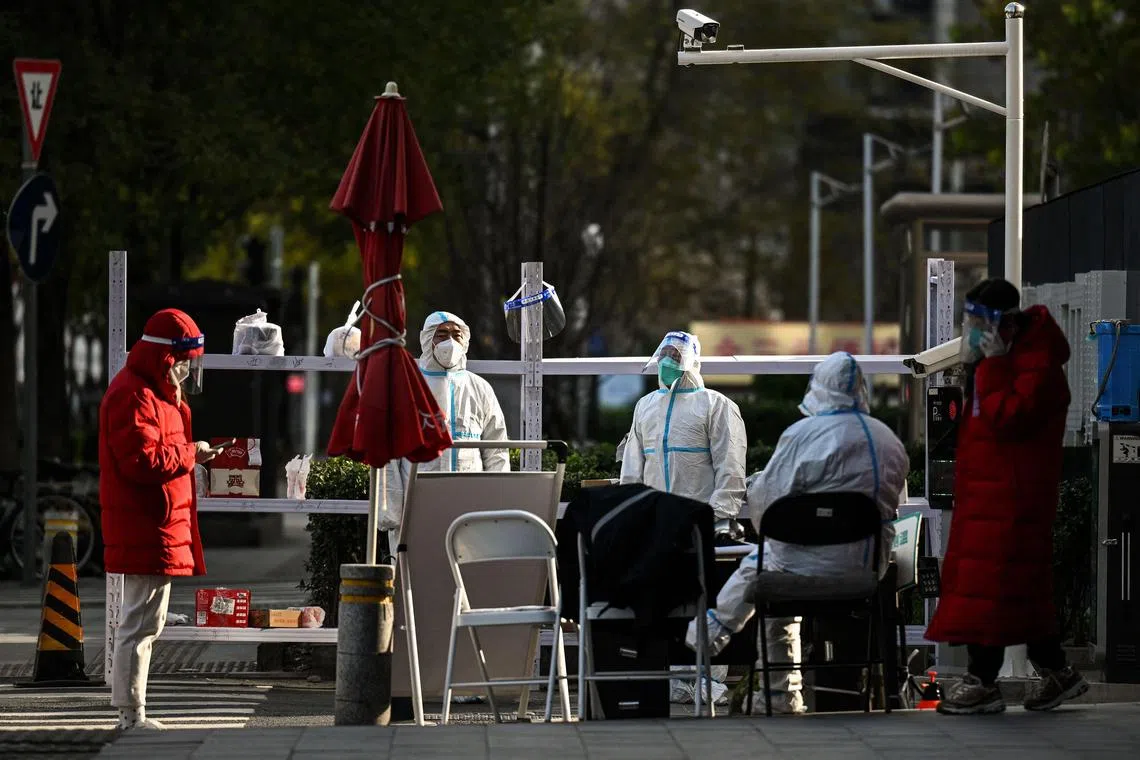 Security personnel guard an entrance to a residential area under lockdown in Beijing on Nov 27, 2022.