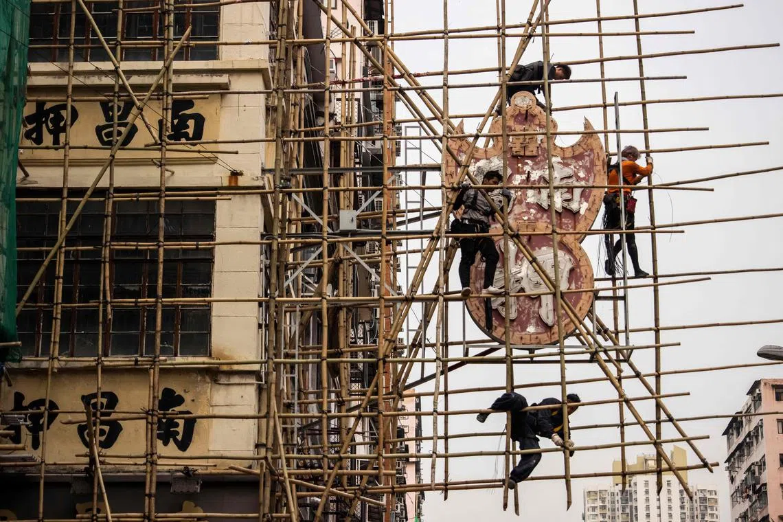 Workers constructing bamboo scaffolding around the Nam Cheong Pawn Shop neon sign before its removal at the requests of the government because of a change in regulations surrounding neon signs, March 9, 2023.