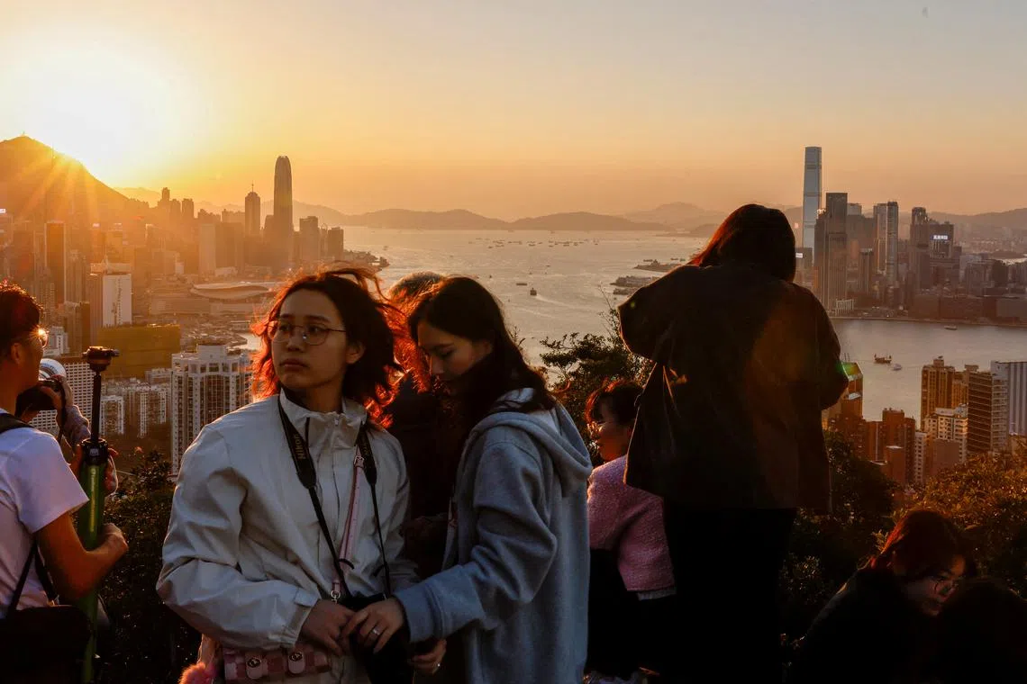 FILE PHOTO: People watch the sunset over Victoria Harbour from a mountaintop in Hong Kong, China March 12, 2024. REUTERS/Tyrone Siu/File Photo