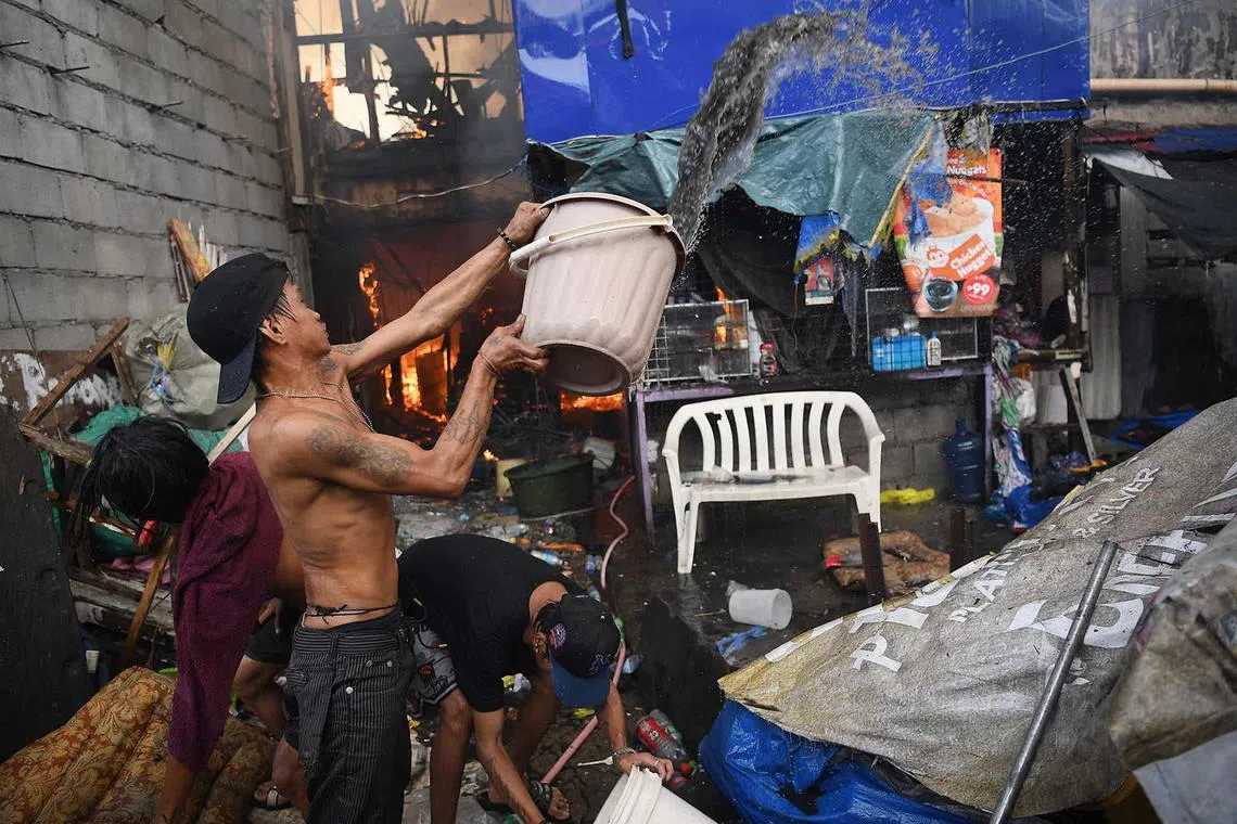 Residents use plastic containers to put out burning houses after a fire gutted homes at an informal settler area in Manila on August 6, 2025. (Photo by Ted ALJIBE / AFP)