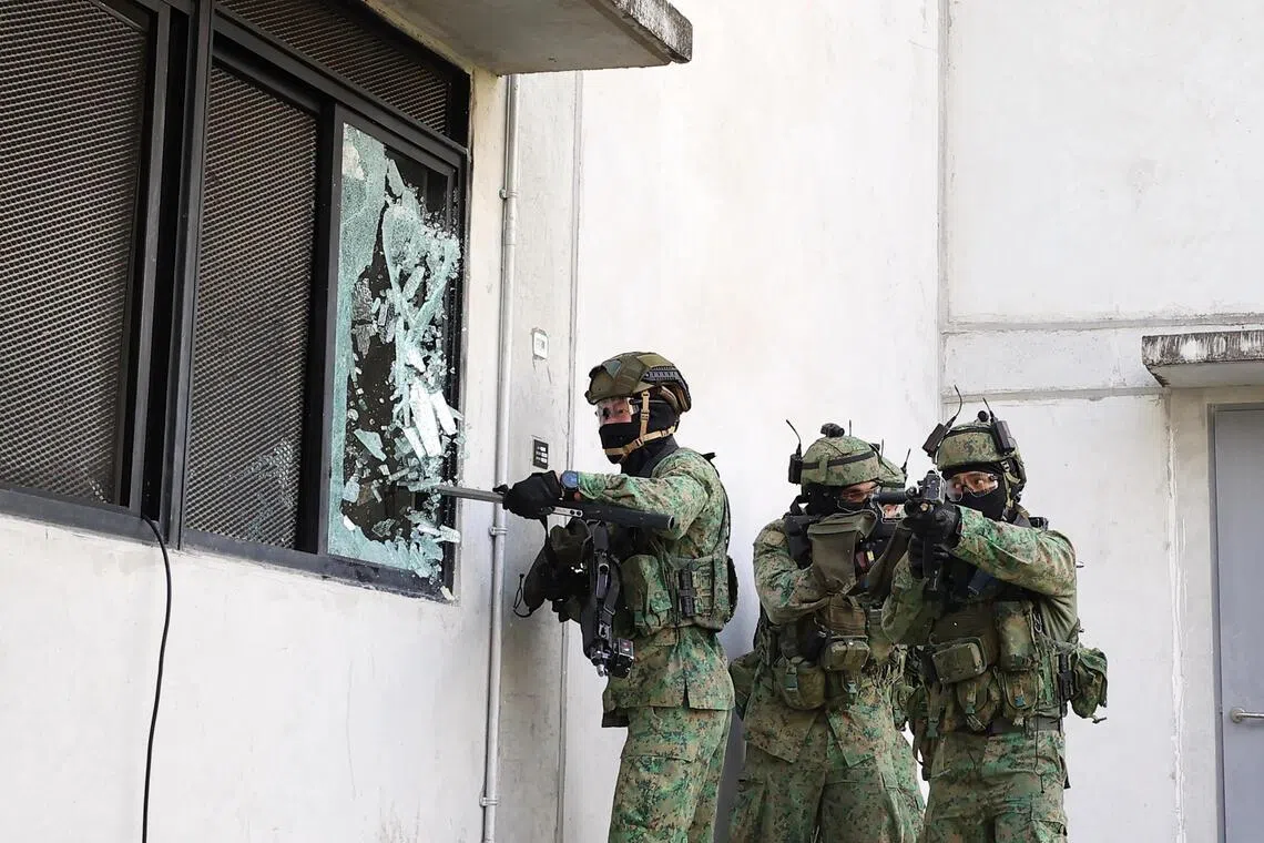 A commando smashes the window of a building at SAFTI City during an urban operations exercise on June 25.