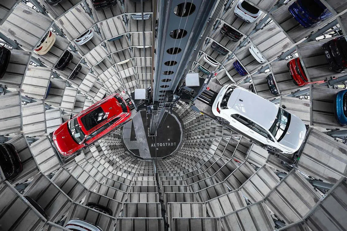 TOPSHOT - A Volkswagen (VW) Passat R and a Golf GTI are pictured in the tower storage facility of German carmaker Volkswagen at the company's headquarters plant in Wolfsburg, central Germany, on March 11, 2025. (Photo by Ronny HARTMANN / AFP)