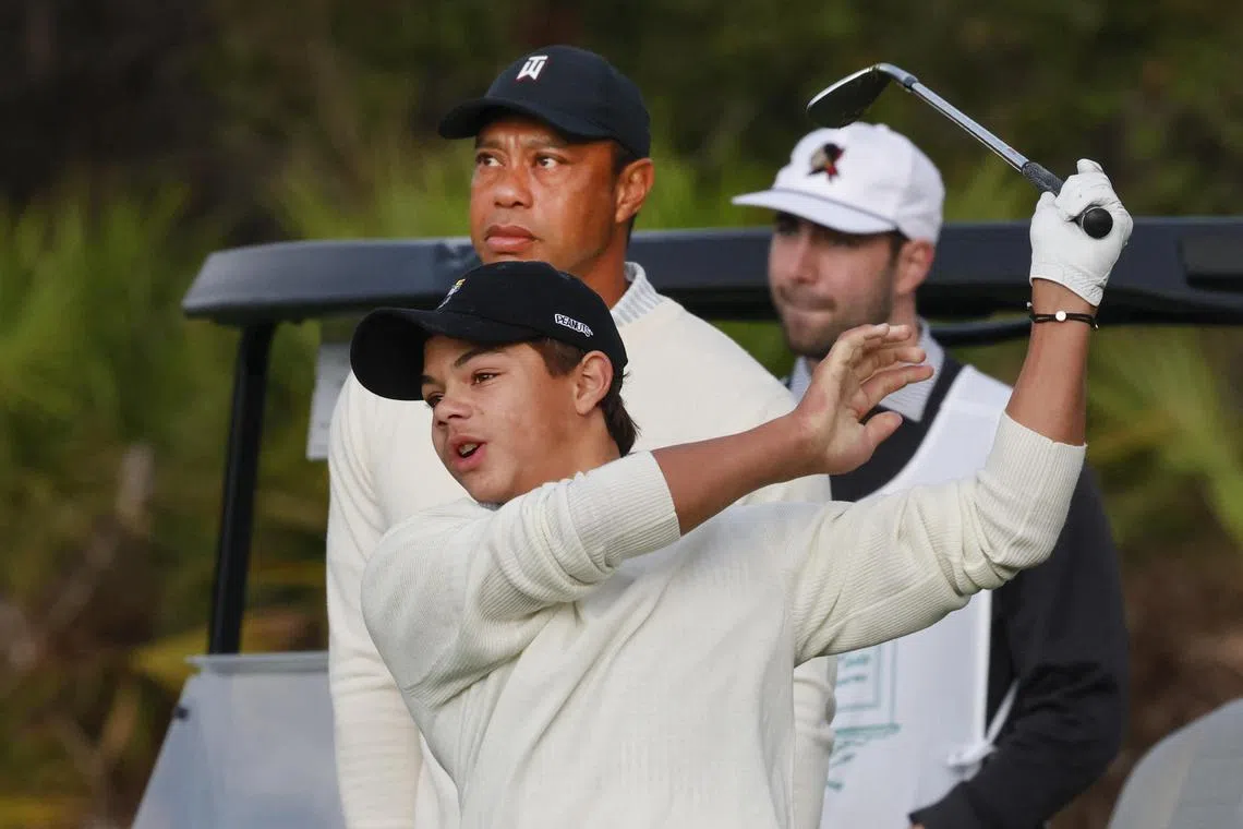 Tiger Woods (top left) watches as his son Charlie Woods (bottom) hits his tee shot on the first hole during a pro-am round of the PNC Championship golf tournament.