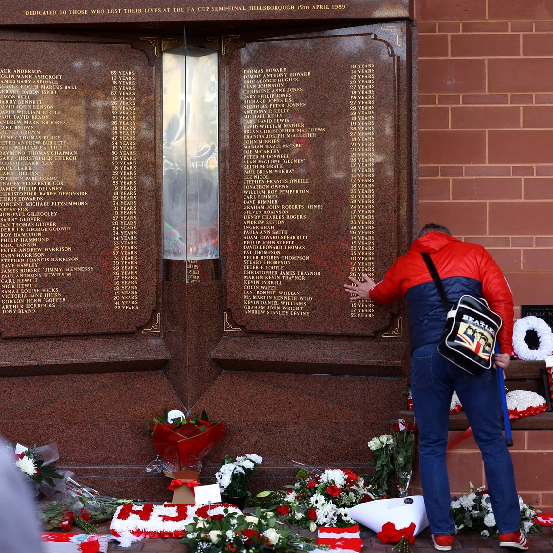 Soccer Football - Premier League - Liverpool v Crystal Palace - Anfield, Liverpool, Britain - April 14, 2024 Fans look at a Liverpool memorial in memory of the victims of the Hillsborough disaster outside the stadium before the match REUTERS/Carl Recine