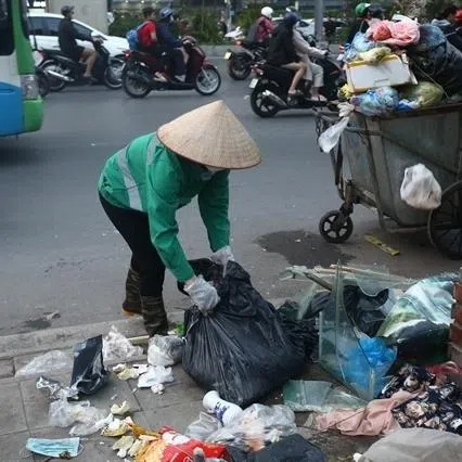 A sanitation worker collecting rubbish at an informal dumping site in Vietnam's capital city Hanoi.