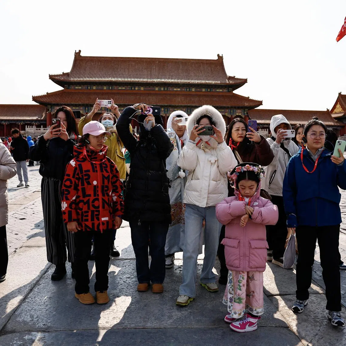 FILE PHOTO: Tourists use their phones as they visit the Forbidden City in Beijing, China February 21, 2025. REUTERS/Tingshu Wang/File Photo