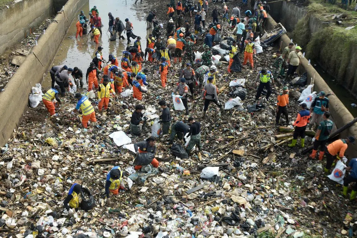 Community members cleaning up trash from the Cikeruh river, which is experiencing a shortage of water, at Ranjuango village in Bandung on July 26, 2023. 