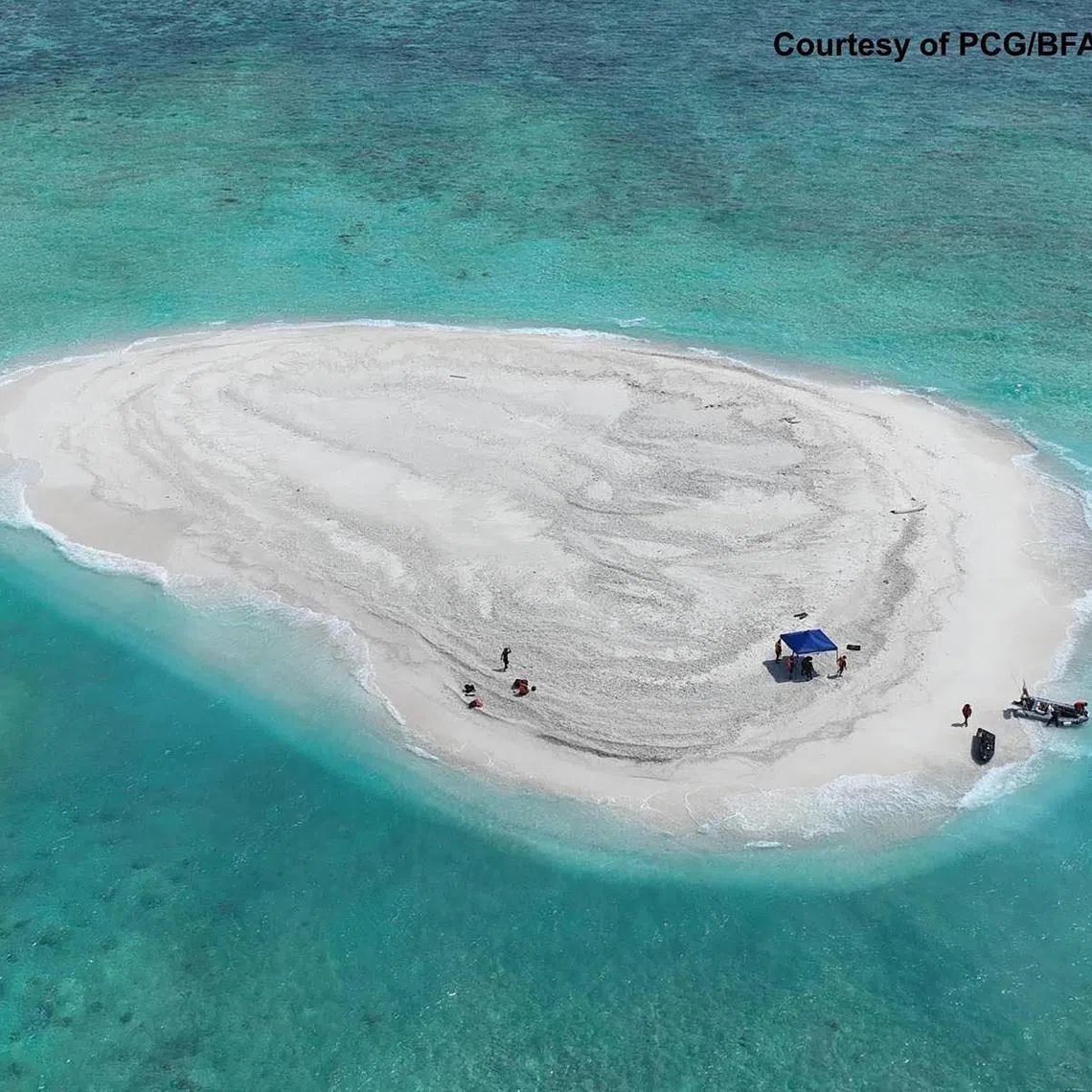 This handout photo taken on March 21, 2024, and received from the Philippine Coast Guard and Bureau of Fisheries and Aquatic Resources (PCG/BFAR) shows an aerial view of Philippine scientists inspecting Sandy Cay reef, near Philippine-held Thitu Island, in the Spratly Islands, in disputed waters of the South China Sea. 
